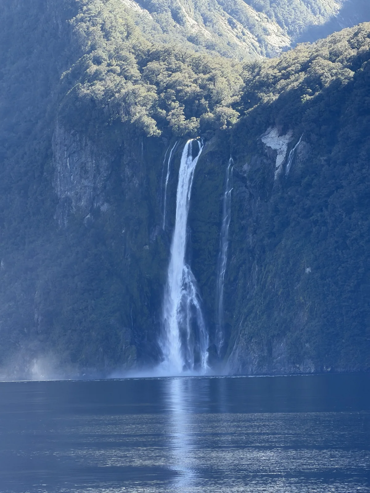 Milford Sound Flight & Cruise — A tall waterfall dropping down cliffs into Milford Sound